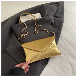 Détail du sac enveloppe métallique doré avec texture ondulée et fine bandoulière chaîne