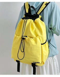 Detail of yellow nylon drawstring backpack showing side pockets and adjustable straps