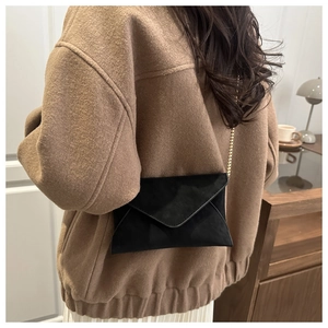 Modische schwarze Umschlag-Umhängetasche mit goldener Kette an einem Modell gezeigt