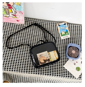 Detail view of black patent leather Ita bag with clear PVC window on checkered background
