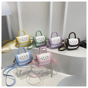 Macro detail of six colorful cherry print crossbody bags on a minimalist white stage