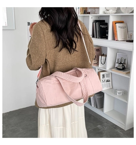 Pink nylon fitness bag with adjustable white shoulder strap carried by a model