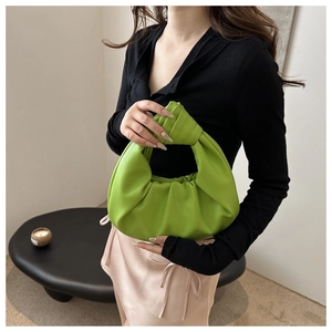 Détail du sac hobo vert vif avec cuir plissé et poignée nouée porté par un mannequin