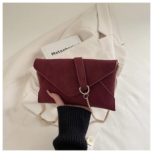 Detailansicht der weinroten Umschlagtasche mit goldener Kette und matter Oberfläche