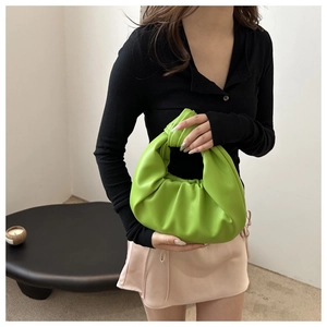 Détail d'un sac hobo plissé vert citron avec une poignée nouée au design distinctif