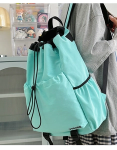 Detail view of mint green drawstring backpack showing nylon texture and side profile of bag