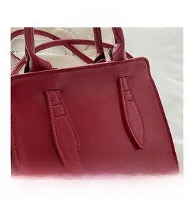 Detail of red faux leather handbag showing glossy crinkled texture and handles