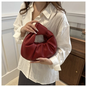 Détail du sac à main en cuir plissé rouge avec poignée nouée et forme de demi-lune