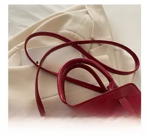 Detail of red textured PU leather handbag with reinforced handle and golden buckle strap