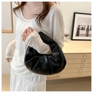 Détail du sac nuage plissé noir minimaliste en cuir brillant porté par un mannequin