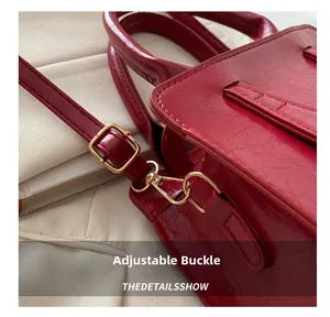 Detail view of the red embossed leather bag featuring a gold buckle and adjustable strap
