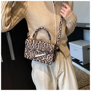 Nahaufnahme einer Leopard-Schultertasche mit goldenen Details zu einem beigen Pulli