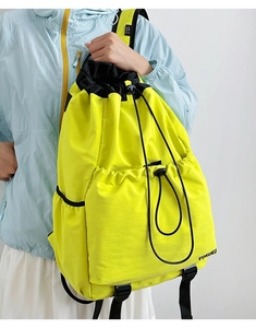 Detail of fluorescent yellow nylon drawstring backpack with drawstring texture and front pocket