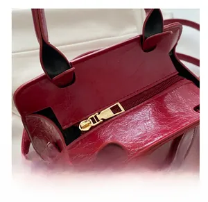 Detail shot of a bright red embossed leather bag featuring a smooth gold metal zipper