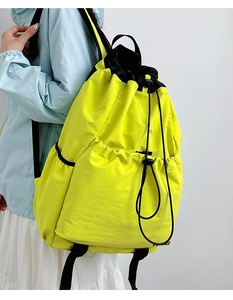 Side view of bright yellow drawstring backpack on model showing large capacity and side pocket