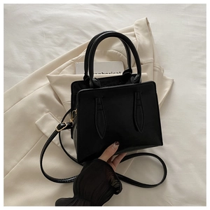 Detail view of a black leather handbag with chic teardrop stitching and slim shoulder strap