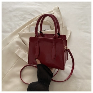 Detailed shot of dark red leather handbag with dual handles and slim shoulder strap
