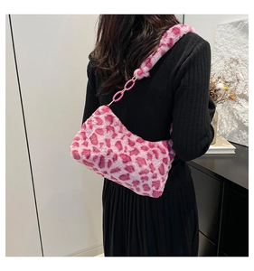 Moderne rosa Leopard-Schultertasche aus Kunstfell mit dekorativer Kette am Model