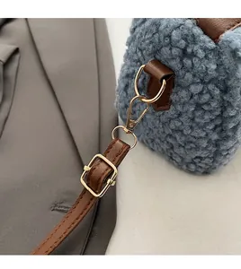 Détail du sac bleu en polaire bouclée avec bandoulière en cuir brun et crochets dorés