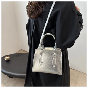 Silver metallic crossbody bag with unique crinkled texture shown on model in a minimalist setting