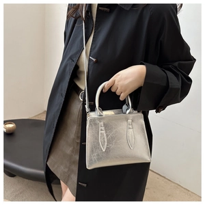 Detailed view of silver metallic handbag with wrinkled leather texture and top handles