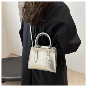 Close-up of silver textured handbag with circular handles on a black coat backdrop