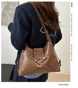 Détail du sac en cuir marron brillant avec lanières croisées et clous en métal doré