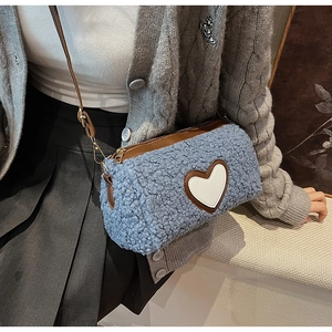Dettaglio della borsa in peluche azzurro con cuore e tracolla in pelle marrone