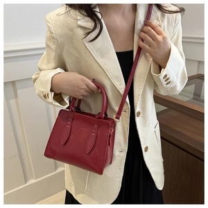 Detail of red glossy patent leather mini tote bag featuring firm structure and slim strap