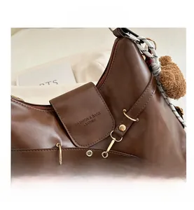 Détail du sac vintage en cuir marron avec boucle dorée et pendentif ours