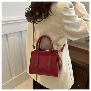 Rear view of a red vintage crossbody bag with polished leather and gold metal buckles
