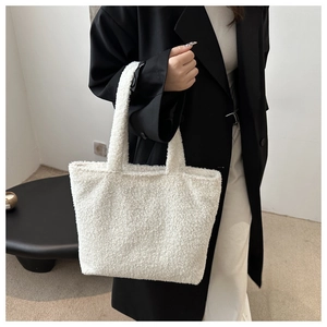 Close-up of fluffy white plush tote bag textured material on a model wearing black coat