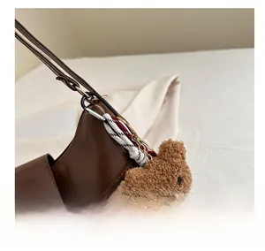 Détail du sac en cuir marron avec logo embossé et breloque ours en peluche mignonne