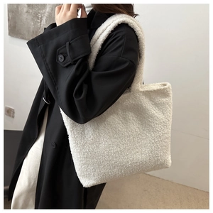 Close-up of fluffy white faux fur tote bag carried by a model in a black winter coat
