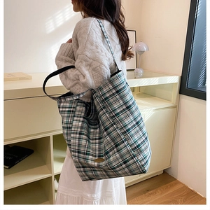 Detalle de bolso tote a cuadros verdes sobre el hombro de la modelo, diseño espacioso y chic
