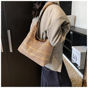 Detail of hobo shoulder bag featuring yellow-brown houndstooth fabric and brown leather trim