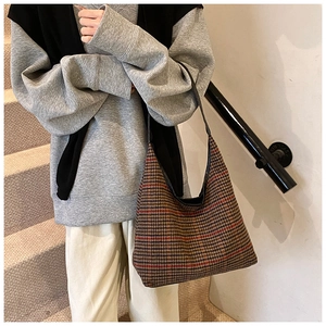 Close-up of brown houndstooth tote bag with slim black strap worn on the shoulder