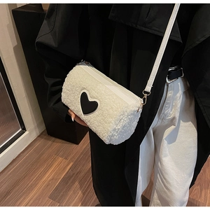Détail du sac bandoulière en peluche blanche avec écusson cœur noir et fermeture éclair