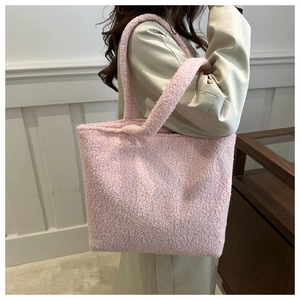 Close-up of the plush pink faux shearling texture and wide shoulder straps on a tote bag