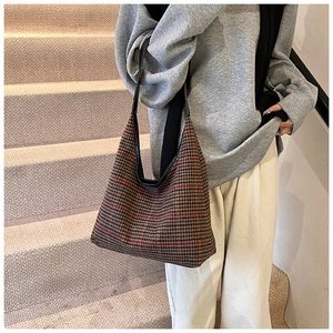 Detailed view of the houndstooth fabric and leather strap on a crescent tote bag