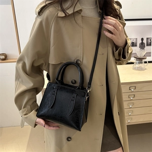 Chic black glossy cracked leather handbag with gold hardware for elegant commute style