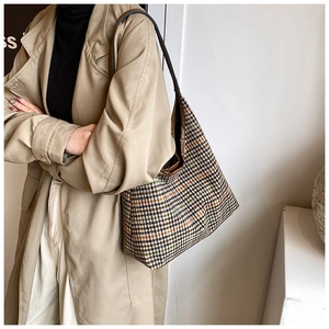 Close-up of houndstooth woven tote bag with brown leather straps for autumn fashion