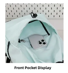 Close-up of front pocket on light green drawstring backpack showing storage for smartphone