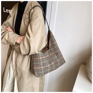 Detail view of houndstooth tote bag featuring woven texture and premium leather strap