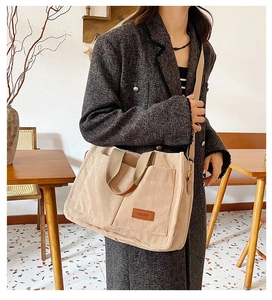 Close-up of beige corduroy tote bag showing textured fabric and fashion leather patch