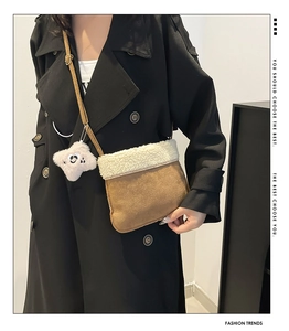 Detail of plush contrast crossbody bag in brown suede and white faux shearling with star charm