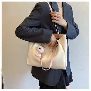 Detail view of off-white tote bag featuring pink straps and a silver metal chain accent