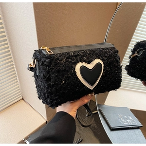 Dettaglio della borsa in peluche nera con patch a cuore e cerniera in metallo dorato