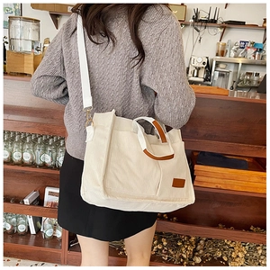Detail of off-white corduroy tote bag with leather handles and long shoulder strap