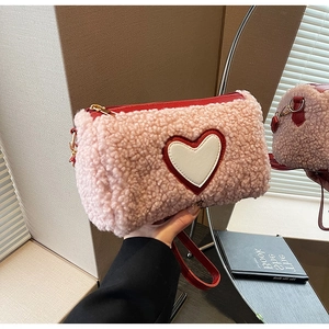 Dettaglio della borsa rosa in pile soffice con toppa a cuore e cerniera rossa vivace